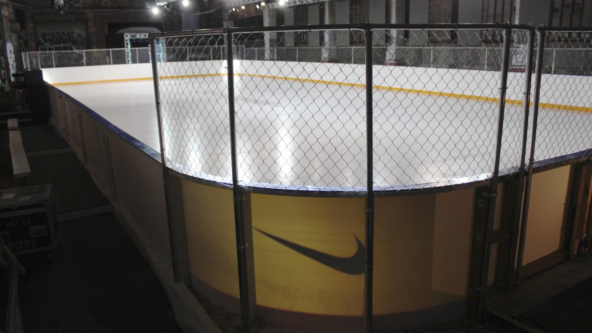 An ice rink enclosed by a fence, showcasing a smooth, frozen surface ready for skating activities.