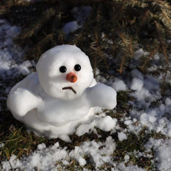 A snowman rests in the snow, showcasing its carrot nose and button eyes against a winter backdrop.