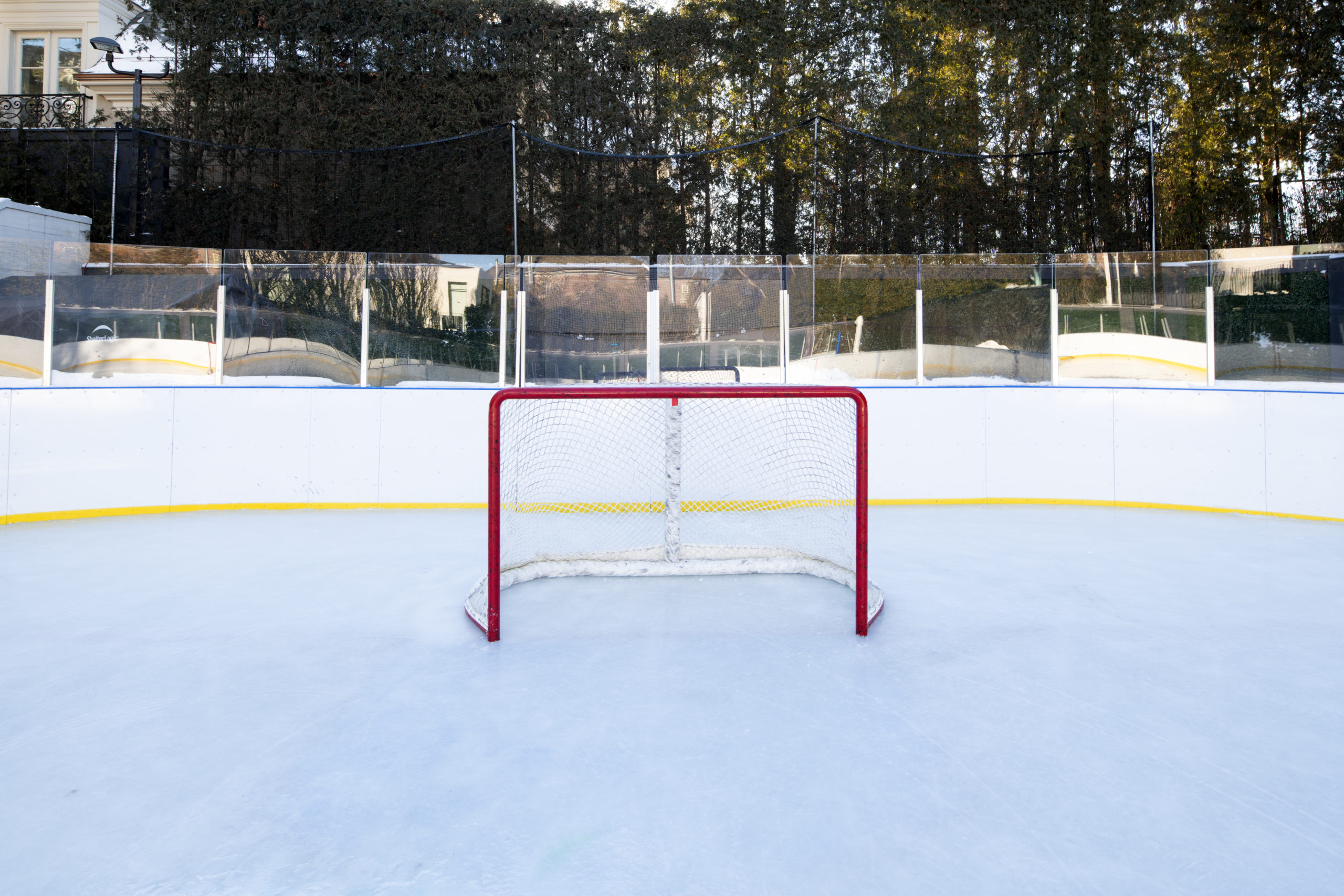An empty ice rink featuring a central goal, showcasing the smooth, pristine surface of the ice.