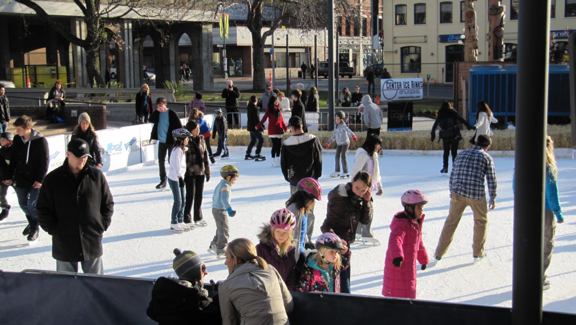 A group of individuals gracefully skating on a smooth ice surface, enjoying a winter day outdoors.