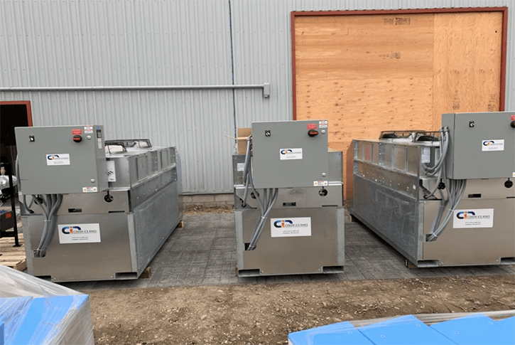 A trio of industrial machines located in front of a building, highlighting their significant role in the industrial landscape.