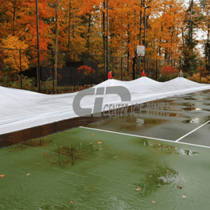 A tennis court is completely covered with a blue tarp, protecting the surface from weather elements.