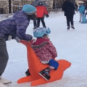 Woman playing in the ice with toddler using seal skate aid